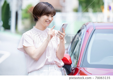 A young woman who parks her car and makes a phone call on her smartphone A young woman who parks her car and makes a phone call on her smartphone 78063135