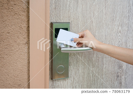 Hand holding key card scanning to unlock wooden door at resort 78063179
