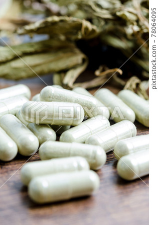 Pile of herbal medicine in capsules with herb dry leaf. Pile of herbal medicine in capsules with herb dry leaf. 78064095
