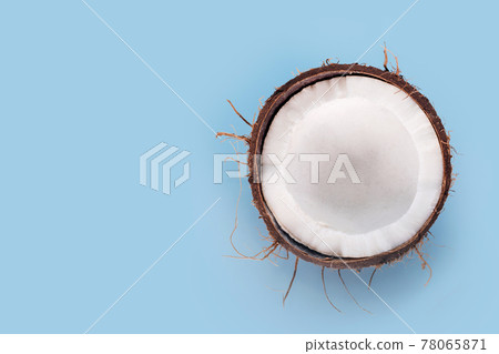 Cracked in half coconut on light blue background. Halved fresh raw coconut, free space for text 78065871