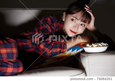 Young woman relaxing watching a movie at night 78068261