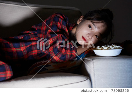 Young woman relaxing watching a movie at night 78068266
