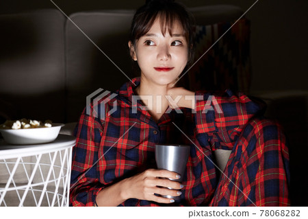 Young woman relaxing watching a movie at night 78068282