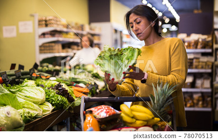 Woman shopping at store, walking among shelves 78070513