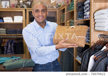 Seller offering suit jacket in menswear boutique Seller offering suit jacket in menswear boutique 78070622