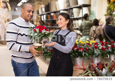 Seller offering gift flower arrangement with roses to male buyer Seller offering gift flower arrangement with roses to male buyer 78070633
