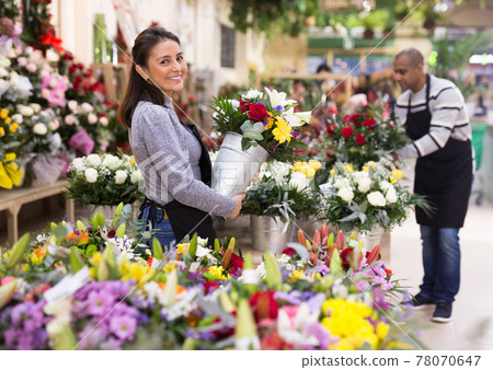 Florist in an apron creates bouquets in flower shop Florist in an apron creates bouquets in flower shop 78070647
