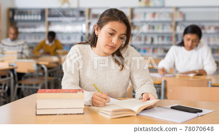 Young adult woman studying in public library Young adult woman studying in public library 78070648
