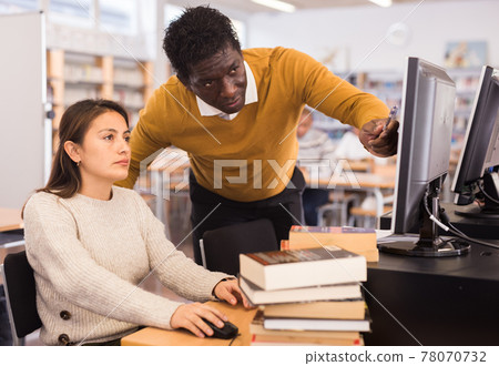 African american man helping young woman in computer library African american man helping young woman in computer library 78070732