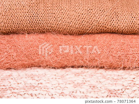 Pile of warm knitted sweaters on a home wardrobe shelf. Clothes in color of living coral. Pile of warm knitted sweaters on a home wardrobe shelf. Clothes in color of living coral. 78071364