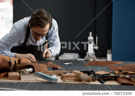 Skilled leather manufacture worker cutting some samples 78073300