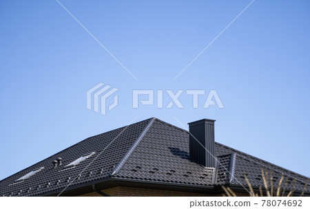Brown corrugated metal profile roof installed on a modern house. The roof of corrugated sheet. Roofing of metal profile wavy shape. Modern roof made of metal. Metal roofing. Brown corrugated metal profile roof installed on a modern house. The roof of corrugated sheet. Roofing of metal profile wavy shape. Modern roof made of metal. Metal roofing. 78074692