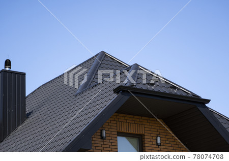Brown corrugated metal profile roof installed on a modern house. The roof of corrugated sheet. Roofing of metal profile wavy shape. Modern roof made of metal. Metal roofing. 78074708