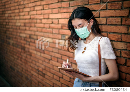 young working asian woman wear surgical mask with tablet at Thapae Gate landmark of Chiang Mai province, Thailand 78080484