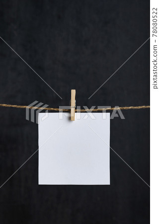 White blank notes hanging with clothespins on rope. Black background. Copy space. Space for your text. Vertical frame 78080522