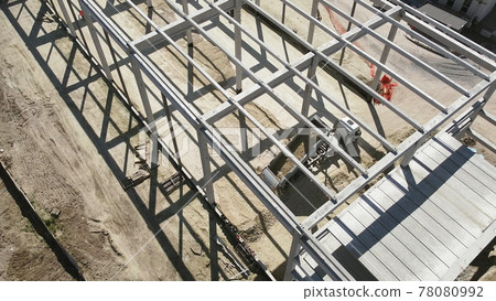 Reinforced Concrete Frame Of An Industrial Building. Camera Flight On A Construction Site. Beams With Steel Reinforcement. Dump Truck Unloads Sand in Construction. Aerial view. Unloading soil Reinforced Concrete Frame Of An Industrial Building. Camera Flight On A Construction Site. Beams With Steel Reinforcement. Dump Truck Unloads Sand in Construction. Aerial view. Unloading soil 78080992