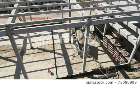 Reinforced Concrete Frame Of An Industrial Building. Camera Flight On A Construction Site. Beams With Steel Reinforcement. Dump Truck Unloads Sand in Construction. Aerial view. Unloading soil Reinforced Concrete Frame Of An Industrial Building. Camera Flight On A Construction Site. Beams With Steel Reinforcement. Dump Truck Unloads Sand in Construction. Aerial view. Unloading soil 78080999