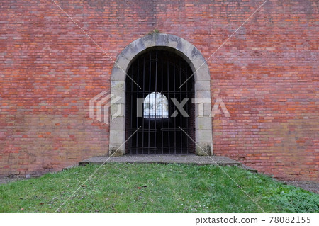 A passage closed by a lattice in an old brick fortress wall. Antique brickwork. 78082155