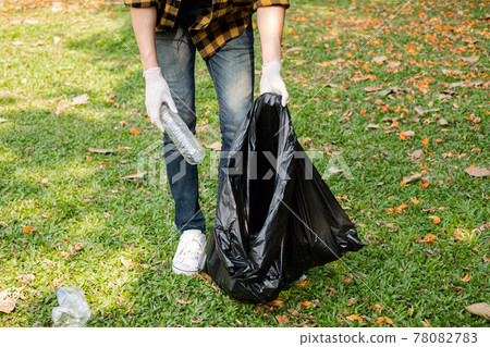 Man's hands pick up plastic bottles, put garbage in black garbage bags to clean up at parks, avoid pollution, be friendly to the environment and ecosystem 78082783