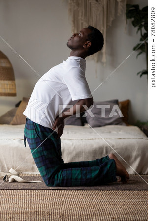 Sporty young african man working out, yoga, pilates or fitness training, standing in asana ushtrasana Sporty young african man working out, yoga, pilates or fitness training, standing in asana ushtrasana 78082809