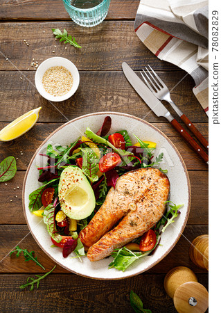 Salmon fish steak grilled, avocado and fresh vegetable salad with tomato, bell pepper and leafy vegetables, top view. 78082829