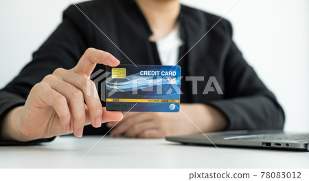 The businesswomen's hand is holding a credit card and using a laptop for online shopping and internet payment The businesswomen's hand is holding a credit card and using a laptop for online shopping and internet payment 78083012