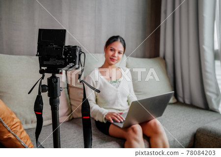 Asian blogger, podcaster or vlogger looking at camera and talking on video shooting with technology 78084203