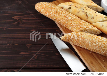 Baguette bread on brown wooden board close up 78085884