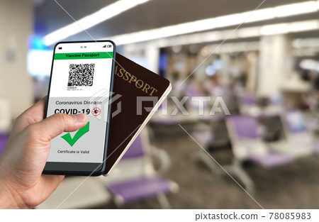 Traveler holds vaccine passport certificate to show COVID 19 vaccination status 78085983