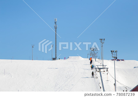 Ski resort, gentle snow slope with people on the lift going to the top. 78087239