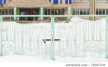 Wide iron gates with light green metal figures of people. 78087244