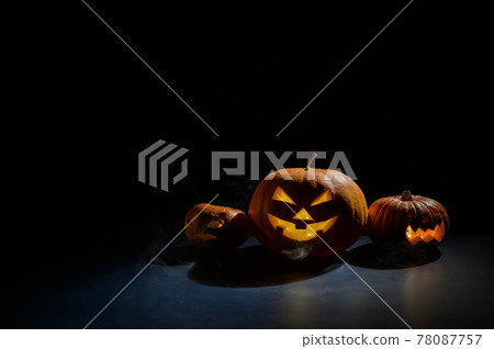 Pumpkins with carved grimaces and candles inside in the dark for halloween. Jack o latern in smoke. Pumpkins with carved grimaces and candles inside in the dark for halloween. Jack o latern in smoke. 78087757
