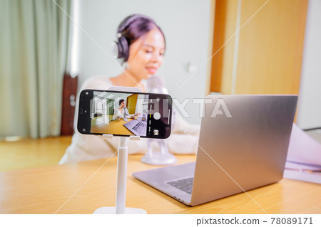 Asian blogger, podcaster or vlogger looking at camera and talking on video shooting with technology Asian blogger, podcaster or vlogger looking at camera and talking on video shooting with technology 78089171