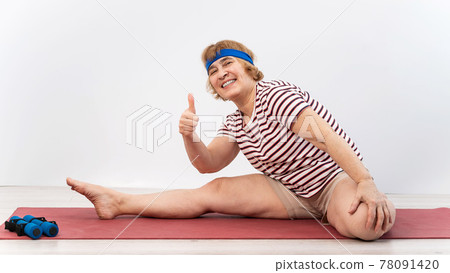 Elderly woman makes bends on a white background. Old lady doing health stretching exercises Elderly woman makes bends on a white background. Old lady doing health stretching exercises 78091420