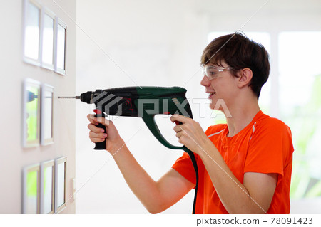 Man drilling wall. Home renovation and decoration. Man drilling wall. Home renovation and decoration. 78091423