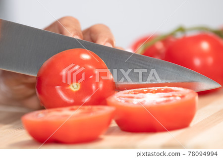 Woman cutting fresh tomato: Selective focus. Diet and healthy food concept Woman cutting fresh tomato: Selective focus. Diet and healthy food concept 78094994