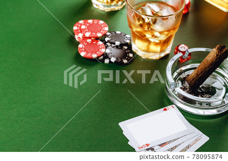 Glass of whiskey, cigar, playing cards and chips on green background Glass of whiskey, cigar, playing cards and chips on green background 78095874