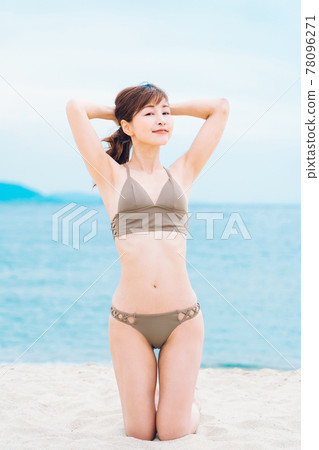 一個穿著泳裝的女人跪在沙灘上 78096271