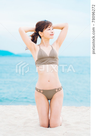 一個穿著泳裝的女人跪在沙灘上 78096272
