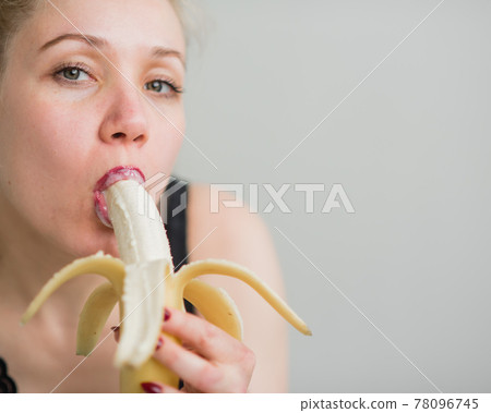 A blonde in black lace lingerie seductively sucks and licks a banana. Woman with sensual red imitates oral pleasure. A blonde in black lace lingerie seductively sucks and licks a banana. Woman with sensual red imitates oral pleasure. 78096745