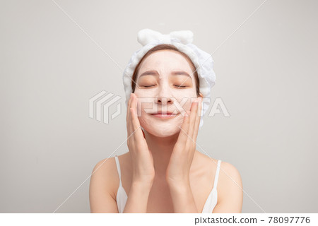Spa dreams. A portrait of a beautiful relaxing lady with a clay mask on her face. 78097776
