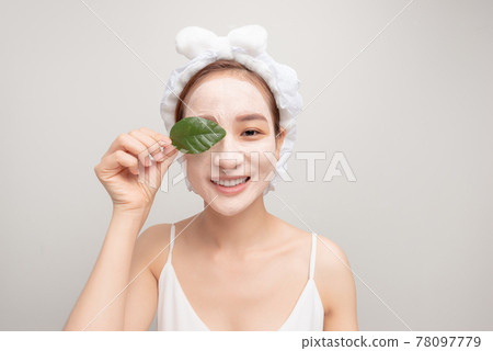 a smiling girl with a white towel on her head applied a clay moisturizing mask 78097779