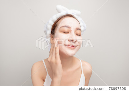 lovely young girl with a white towel on her head applied a useful clay mask on her face, smiling lovely young girl with a white towel on her head applied a useful clay mask on her face, smiling 78097808