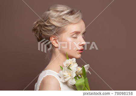 Magnificent young woman with bridal hairstyle and white tulip flowers on brown background 78098158