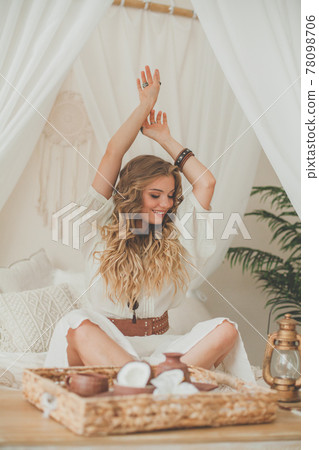 Happy woman with blonde curly hair resting in white hotel room at a tropical resort 78098706