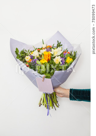 Hyacinths, yellow and orange tulips and white daffodils flowers in hand on white Hyacinths, yellow and orange tulips and white daffodils flowers in hand on white 78099473