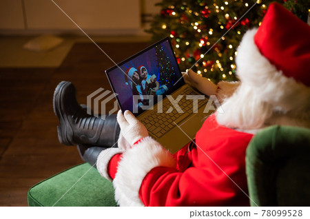 Happy mom and son talking to santa claus by video chat on a laptop. Woman and boy remotely wishes Merry Christmas 78099528