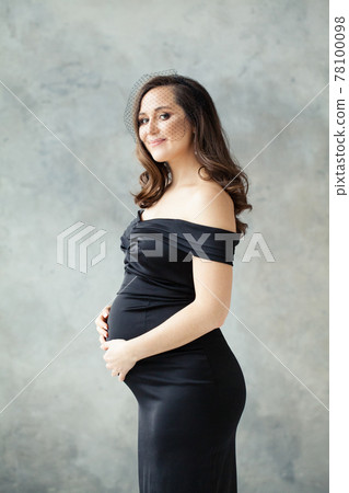 Fashion portrait of pregnant woman in black dress on gray 78100098