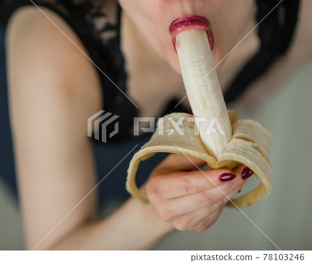 A blonde in black lace lingerie erotically sucks and licks a banana. Unrecognizable woman with sensual red imitates oral pleasure. A blonde in black lace lingerie erotically sucks and licks a banana. Unrecognizable woman with sensual red imitates oral pleasure. 78103246