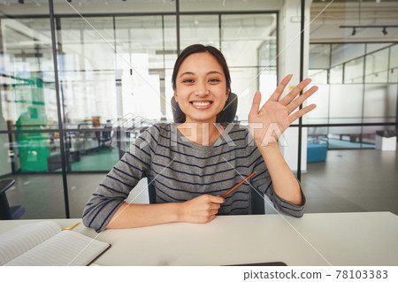 Easy-going woman sitting at table and waving her hand Easy-going woman sitting at table and waving her hand 78103383